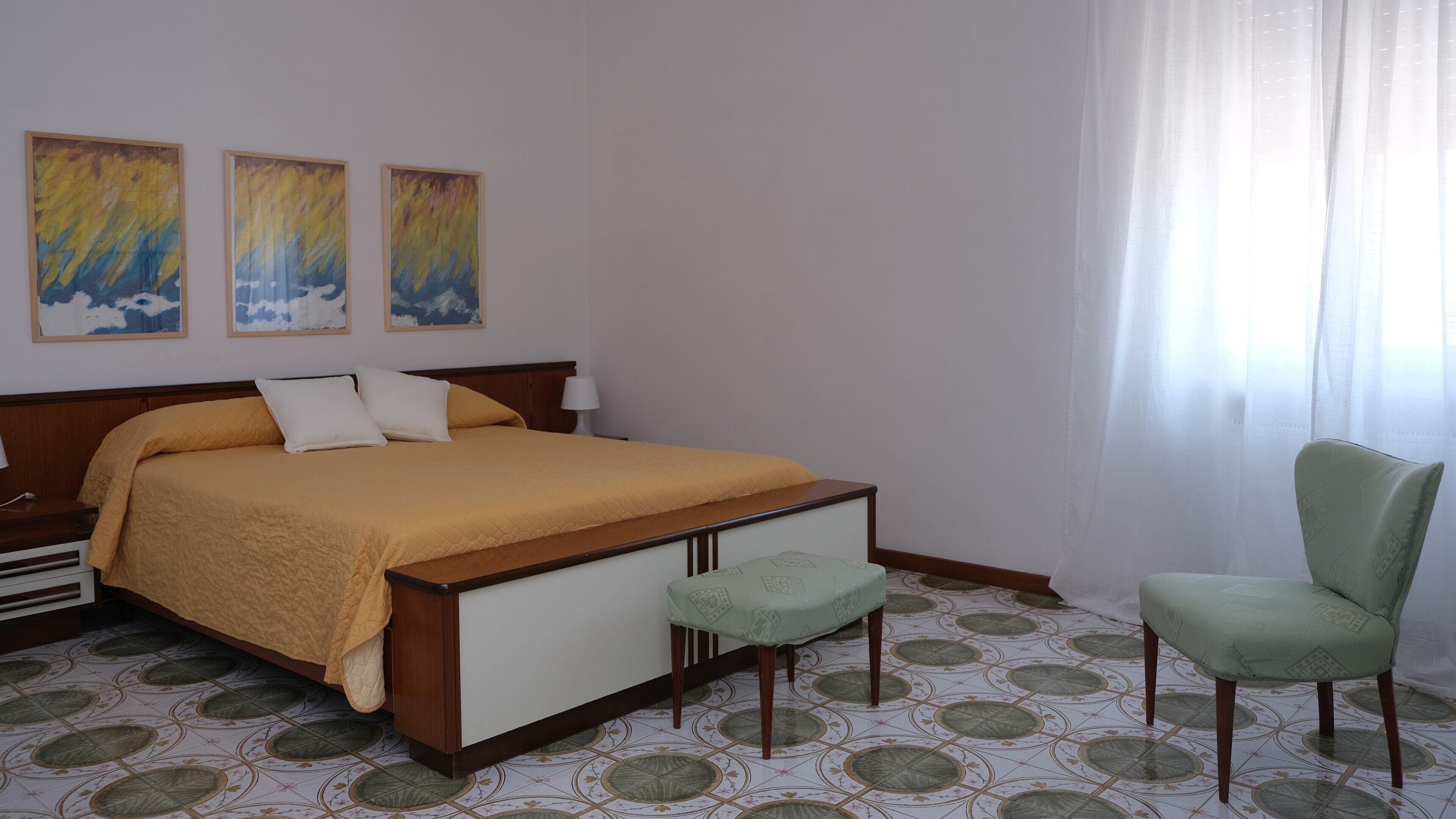 Ein Hotelzimmer mit einem Bett, einem Sessel und drei Bildern an der Wand.
