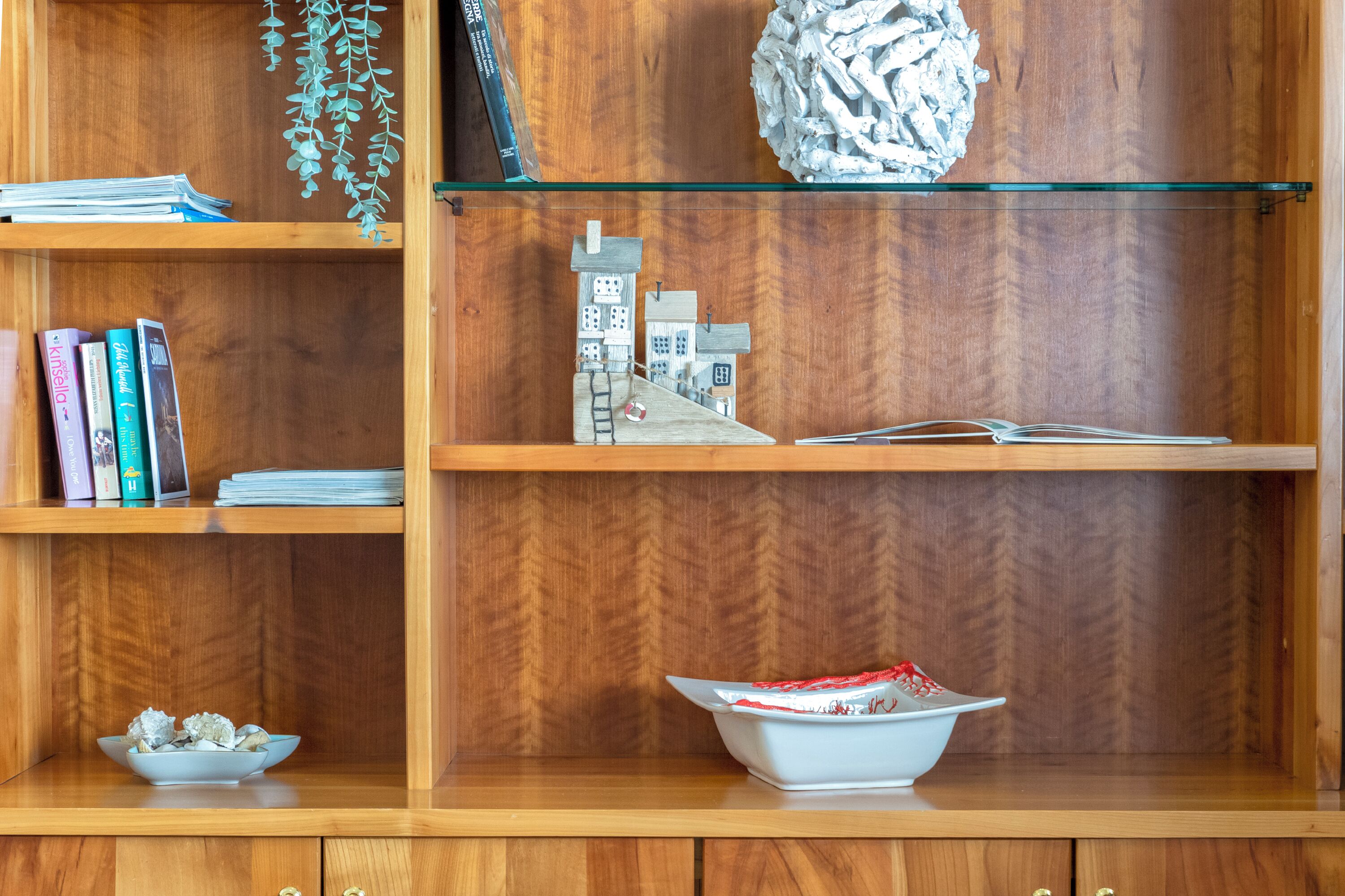 A wooden bookshelf with books, a small model house, and decorative items.
