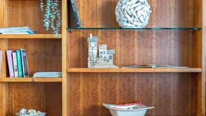 Une bibliothèque en bois remplie de livres, une petite maquette de maison et quelques objets décoratifs.