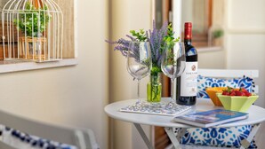 Une petite table ronde avec deux verres à vin, une bouteille de vin et un bol de fraises.