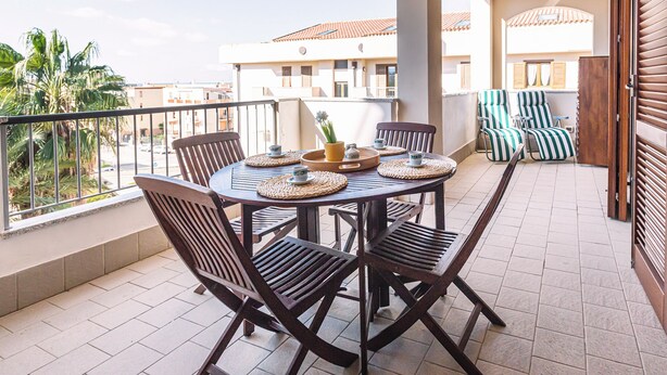 A balcony with a round table, four chairs, and a small potted plant.