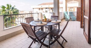 A balcony with a round table, four chairs, and a small potted plant.