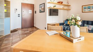 A living room with a wooden table, a sofa, a TV, and a bookshelf.