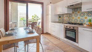 A kitchen with white cabinets, a stove, and a dining area with a table set for four.