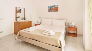Een netjes ingerichte hotelkamer met een groot bed, een houten dressoir, een nachtkastje met een lamp en een schilderij aan de muur.