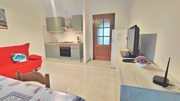 A compact living space with a kitchenette, a dining area, and a television.