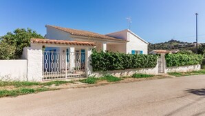 Une maison à deux étages, avec une façade blanche, un toit en tuiles et une entrée fermée par un portail.