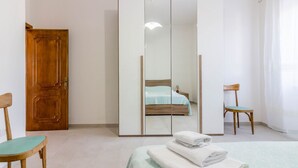Une chambre à coucher avec un lit, une armoire en bois, une chaise et un miroir.