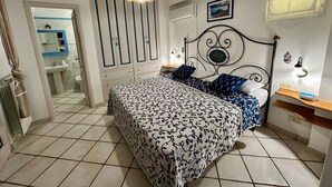 A bedroom with a bed, bedside table, and a hanging light fixture.