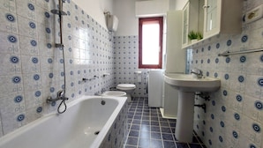 Ein Badezimmer mit Badewanne, Toilette und Waschbecken, alles mit blauen, floralen Fliesenmustern.