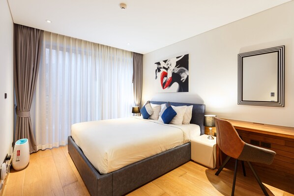 Una habitación de hotel moderna con una cama grande, un escritorio y una silla.