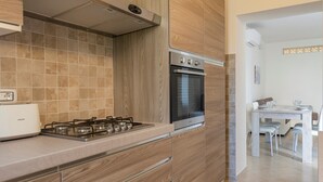 A modern kitchen with a gas stove, oven, and wooden cabinetry.