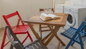A small kitchenette with a wooden table, two chairs, a book, and a washing machine.
