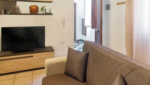 A living room with a sofa, a flat-screen TV, and a wooden coffee table. - Machin 3 - One Bedroom Apartment, Sleeps 2 (Alghero)