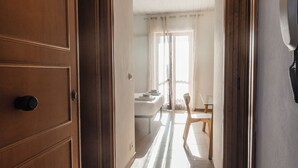 Un pasillo que conduce a una habitación con cama, una silla y una mesa.