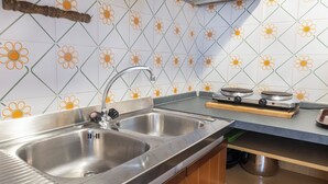 Una cocina con dos lavamanos de acero inoxidable, una tabla de cortar de madera y una cafetera.