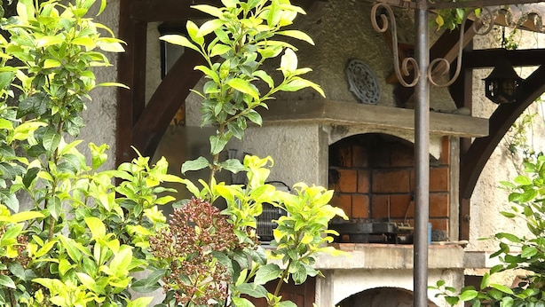 A stone building with a rustic, arched doorway and a brick fireplace.