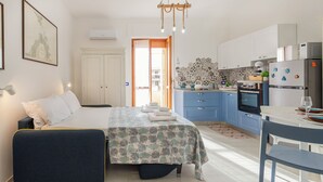 Une chambre d’hôtel moderne équipée d’un lit, d’un bureau, d’une kitchenette et d’une salle de bain.