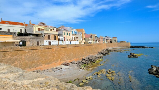 A coastal town with a stone wall and buildings along the waterfront.