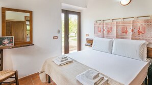 Un dormitorio con una cama, una silla, un escritorio con espejo y una ventana.