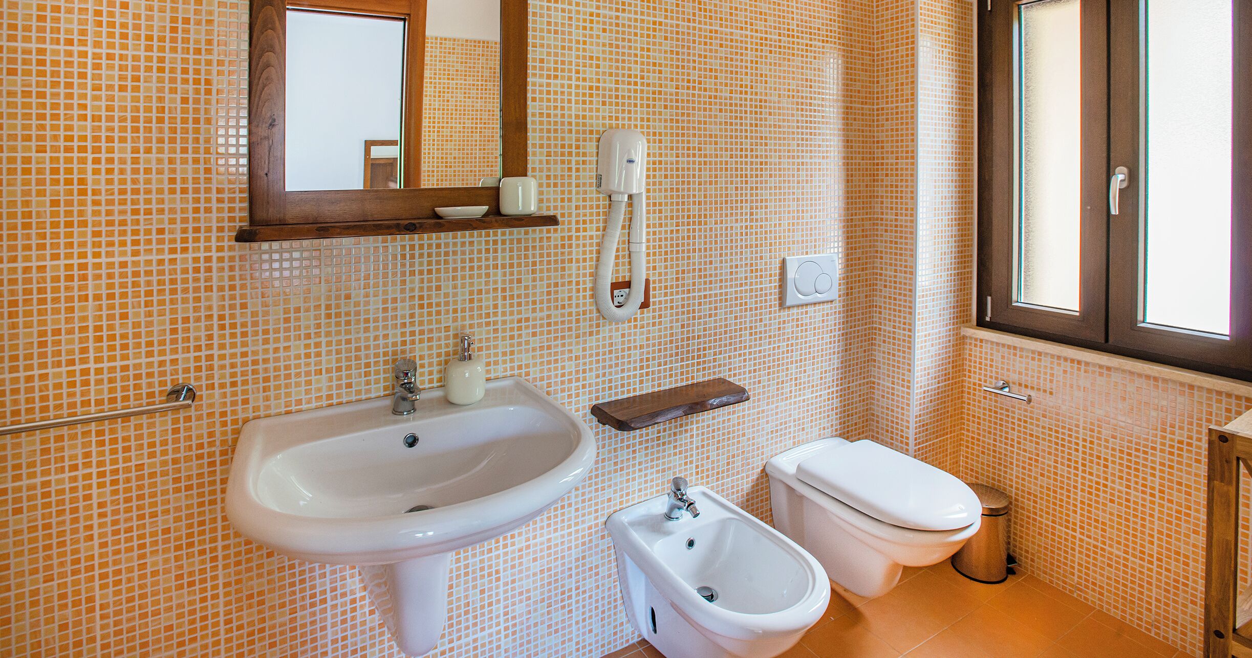 A bathroom with a sink, bidet, toilet, and a mirror above the sink.