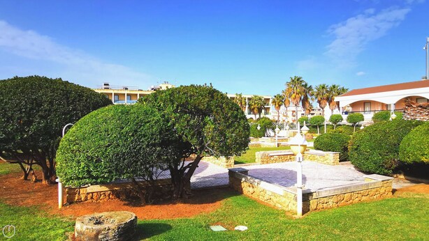 A well-maintained garden with neatly trimmed hedges, a stone fountain, and a paved walkway.