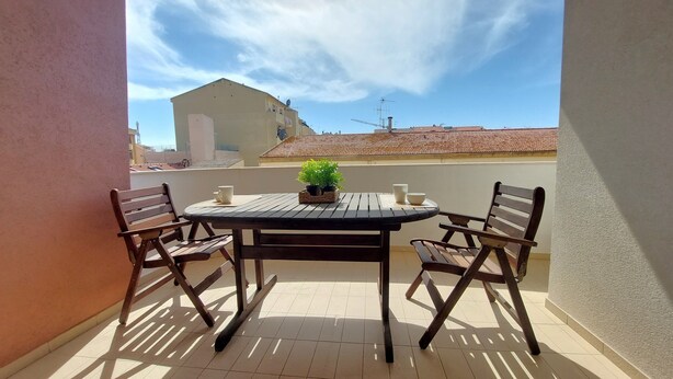 A small outdoor balcony with a round wooden table and two wooden chairs.
