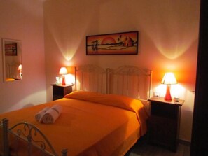 A hotel room with a bed, two bedside lamps, a painting on the wall, and a mirror. - ECODAL MARE (Gallipoli)