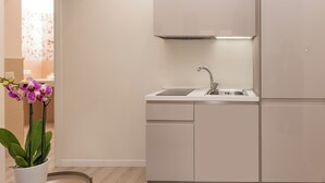 A modern kitchen with white cabinetry, a stainless steel sink, and a built-in oven. - Best Vatican Apartment (Rome)