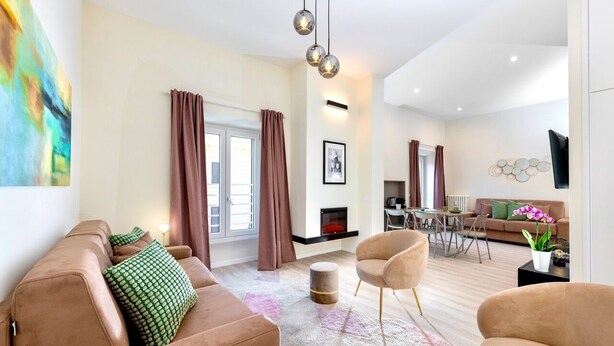 A modern living room with a sofa, armchairs, a fireplace, and a dining area. - Best Vatican Apartment (Rome)