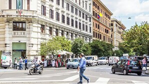 A busy urban street with pedestrians, vehicles, and buildings. - Best Vatican Apartment (Rome)
