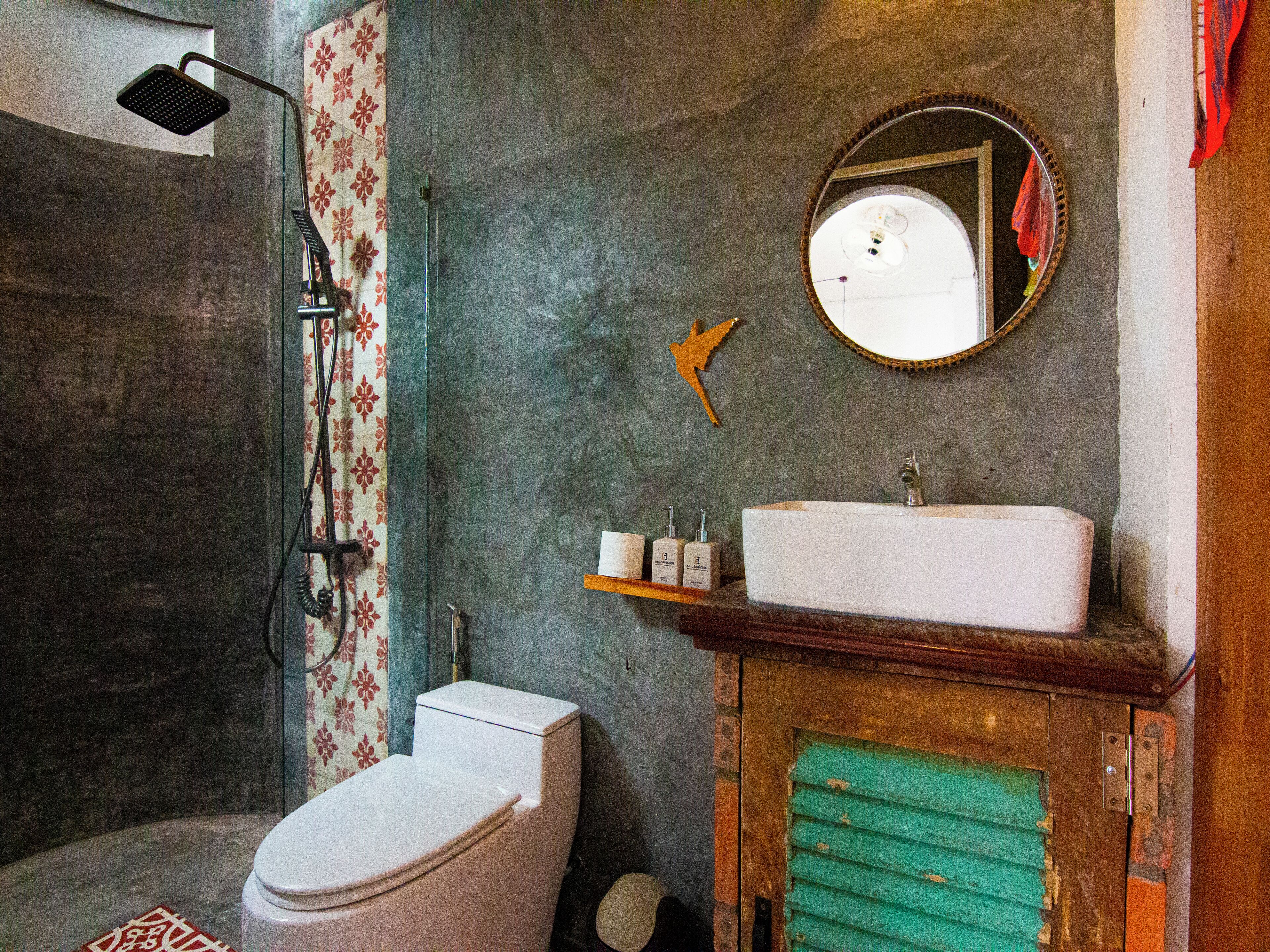 Een badkamer met toilet, douche, wastafel en spiegel.