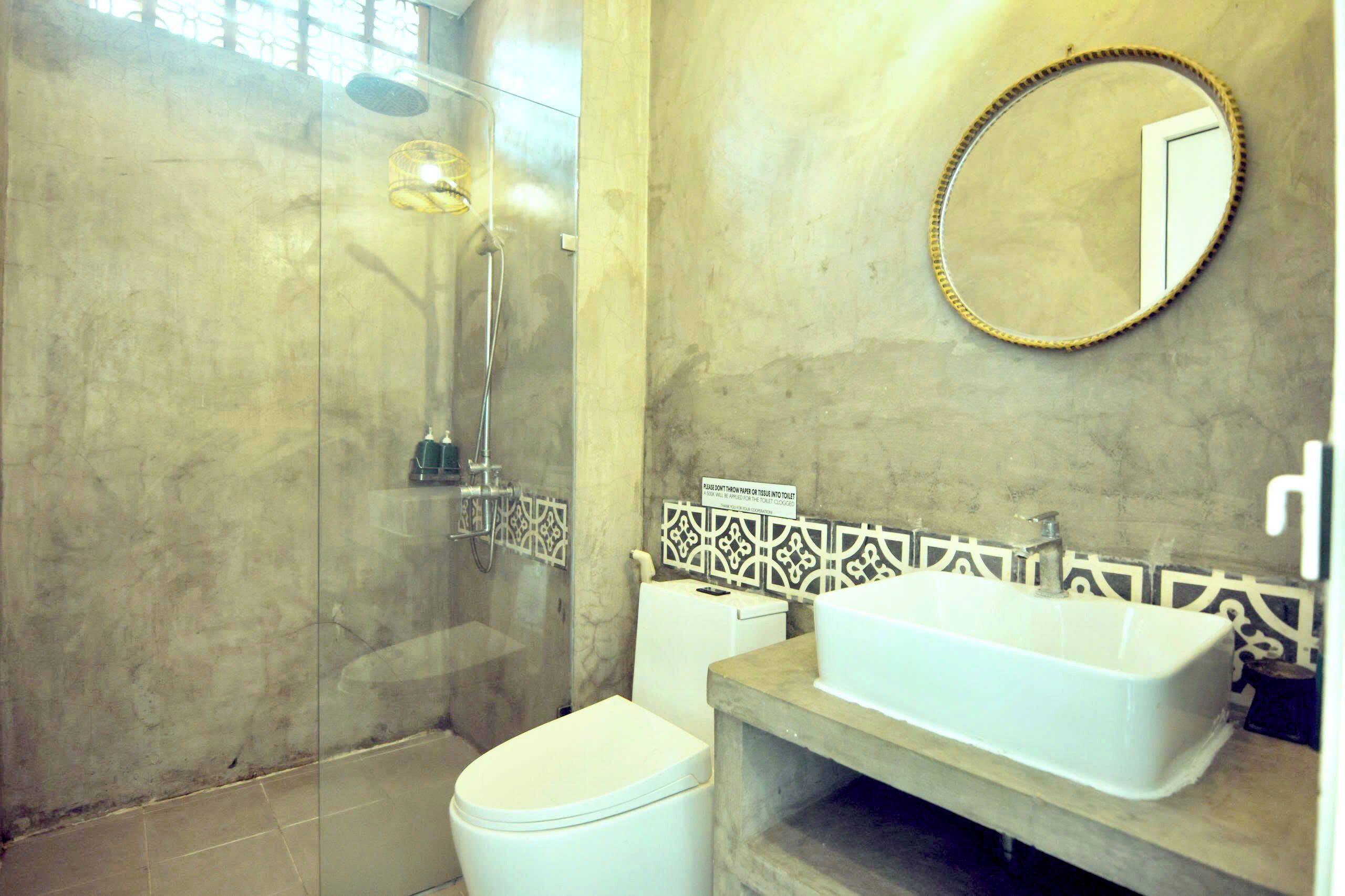 A bathroom with a glass-enclosed shower, a white toilet, and a sink with a mirror above it.