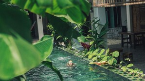 A swimming pool with clear water, surrounded by lush greenery and a wooden deck. - IAM SAIGON Homestay (Ho Chi Minh City)