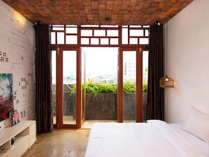 A bedroom with a bed, a desk, a view through a sliding door, and a brick ceiling. - IAM SAIGON Homestay (Ho Chi Minh City)