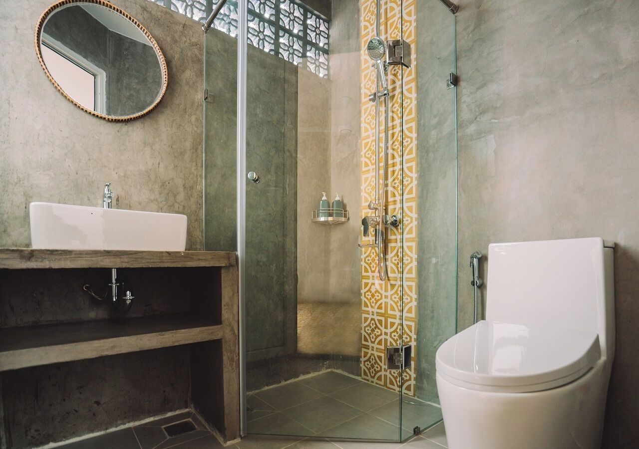Un baño con ducha de vidrio, lavamanos e inodoro.