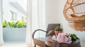 Una habitación moderna con una mesa redonda, una silla, una planta en maceta y un sillón colgante de mimbre.