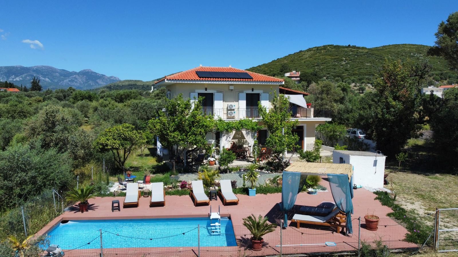 A villa with a swimming pool, outdoor seating, and a view of mountains.