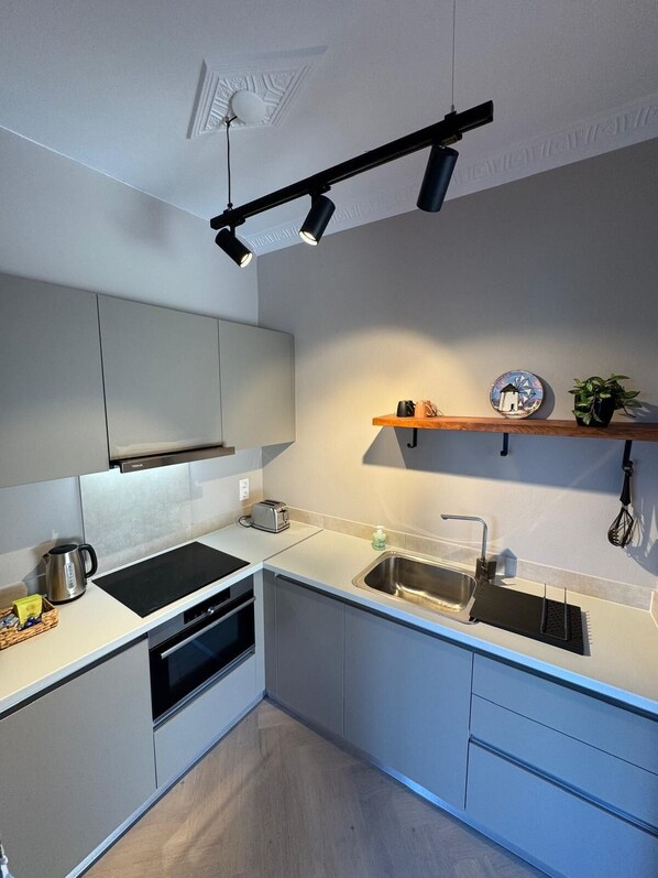 A modern kitchen with a built-in oven, a sink, and a countertop with a toaster. - Villa Feronia Samos (Mesokampos)