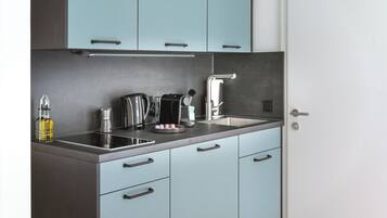 A compact kitchen with light blue cabinets, a stainless steel sink, and modern appliances.