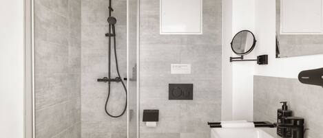 A modern bathroom with a glass-enclosed shower, a white toilet, a sink with a mirror, and a wall-mounted heater.