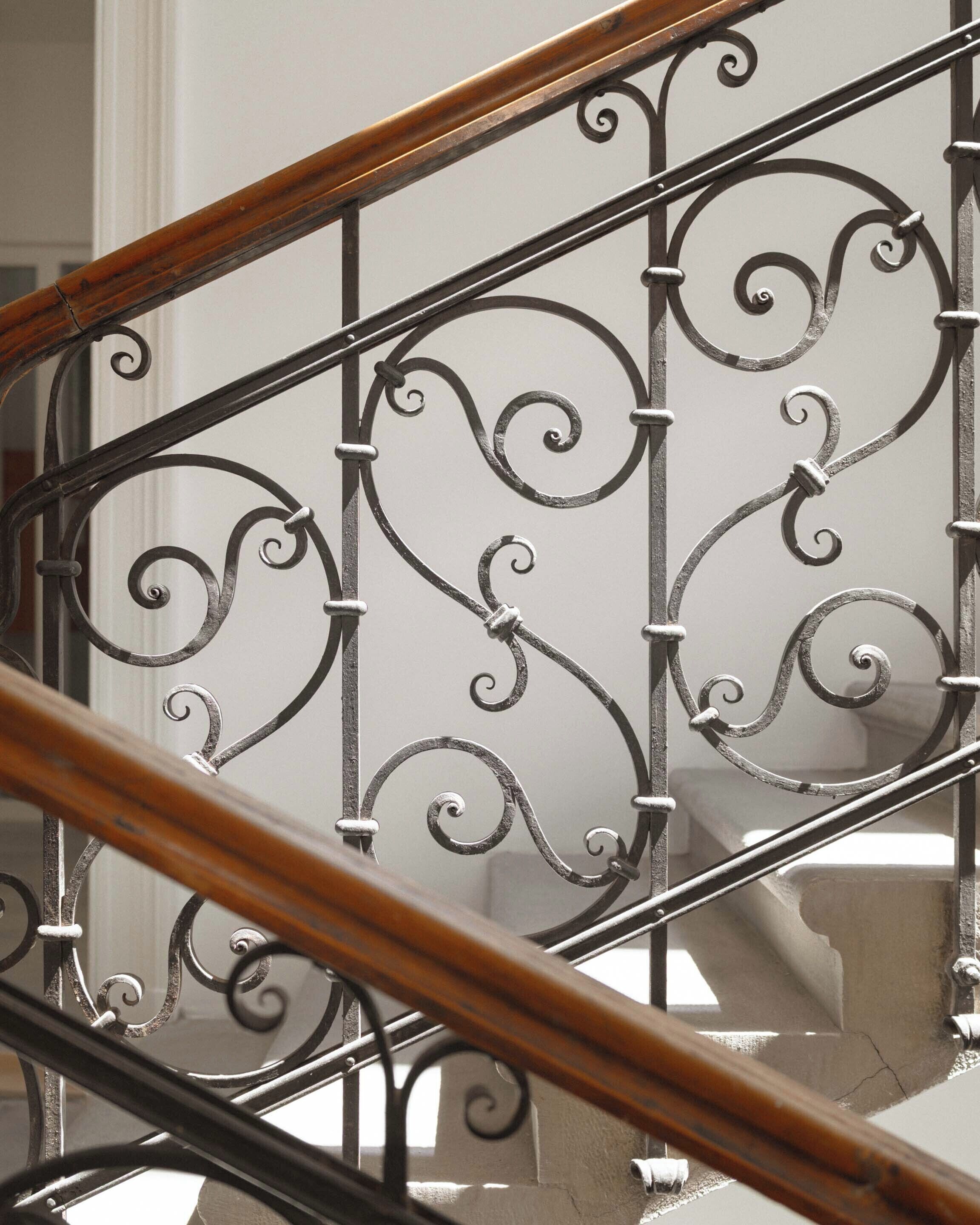 A staircase with ornate metal railings and wooden handrails.