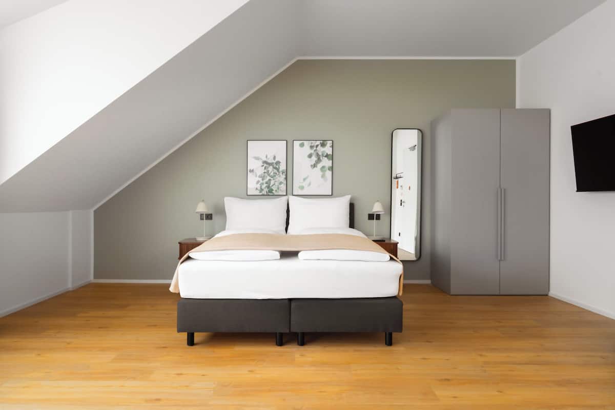 A modern bedroom with a bed, two bedside tables, a wardrobe, and artwork on the wall.
