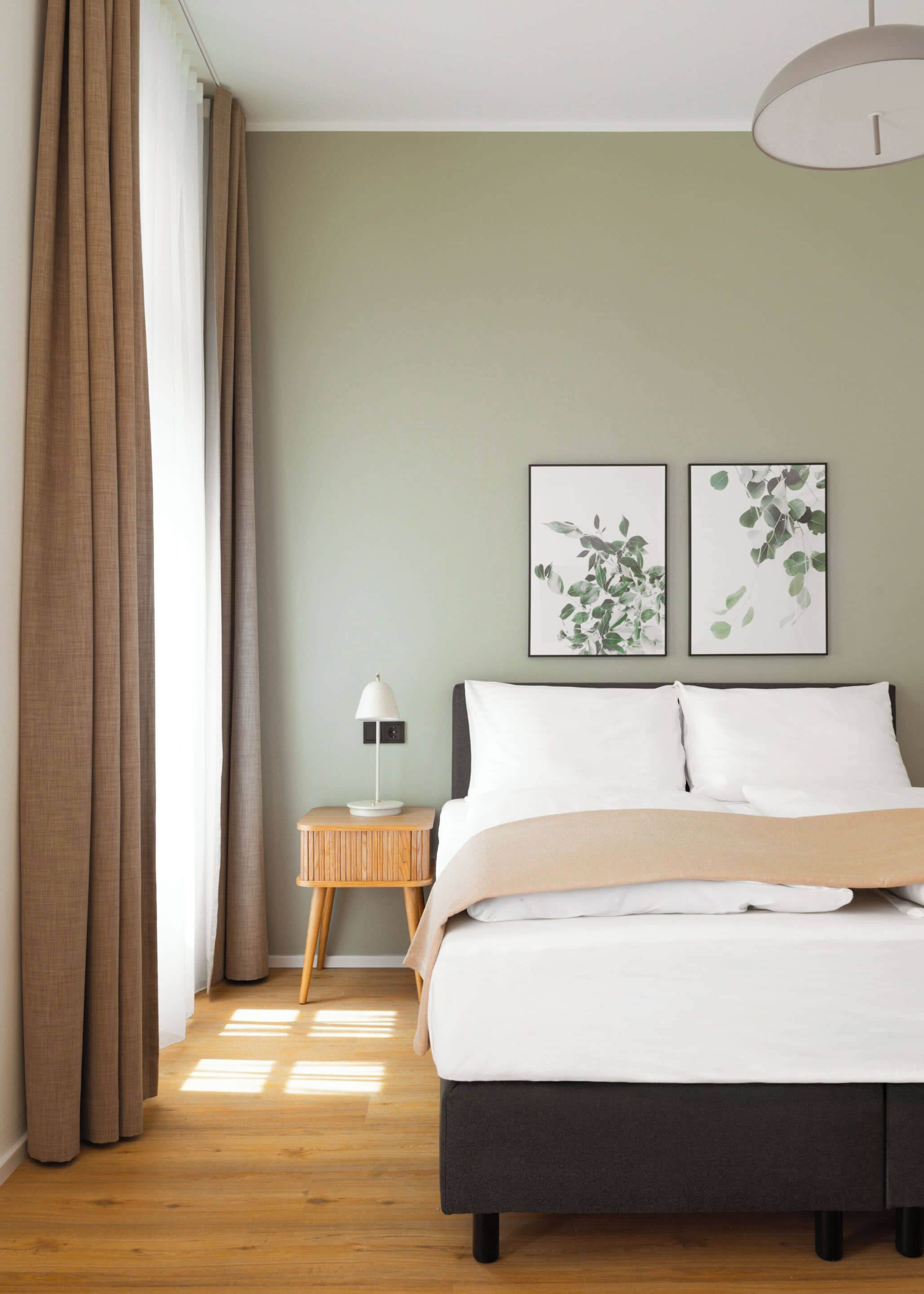 A bedroom with a bed, a nightstand, a lamp, and two framed pictures on the wall.