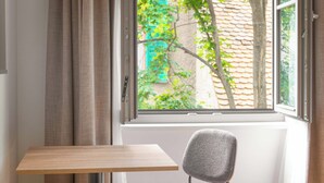A room with a window, a table, a chair, and a bed. - Limehome Graz Trauttmansdorffgasse (Graz)