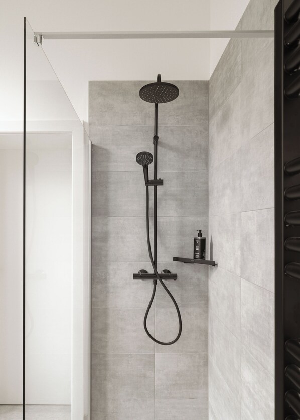 Una ducha moderna con cabezal de ducha de lluvia y cabezal de ducha de mano, montada en una pared de diseño minimalista.