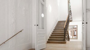 A staircase with a wooden handrail and a metal railing, leading to a room with a door and a window. - Limehome Graz Trauttmansdorffgasse (Graz)