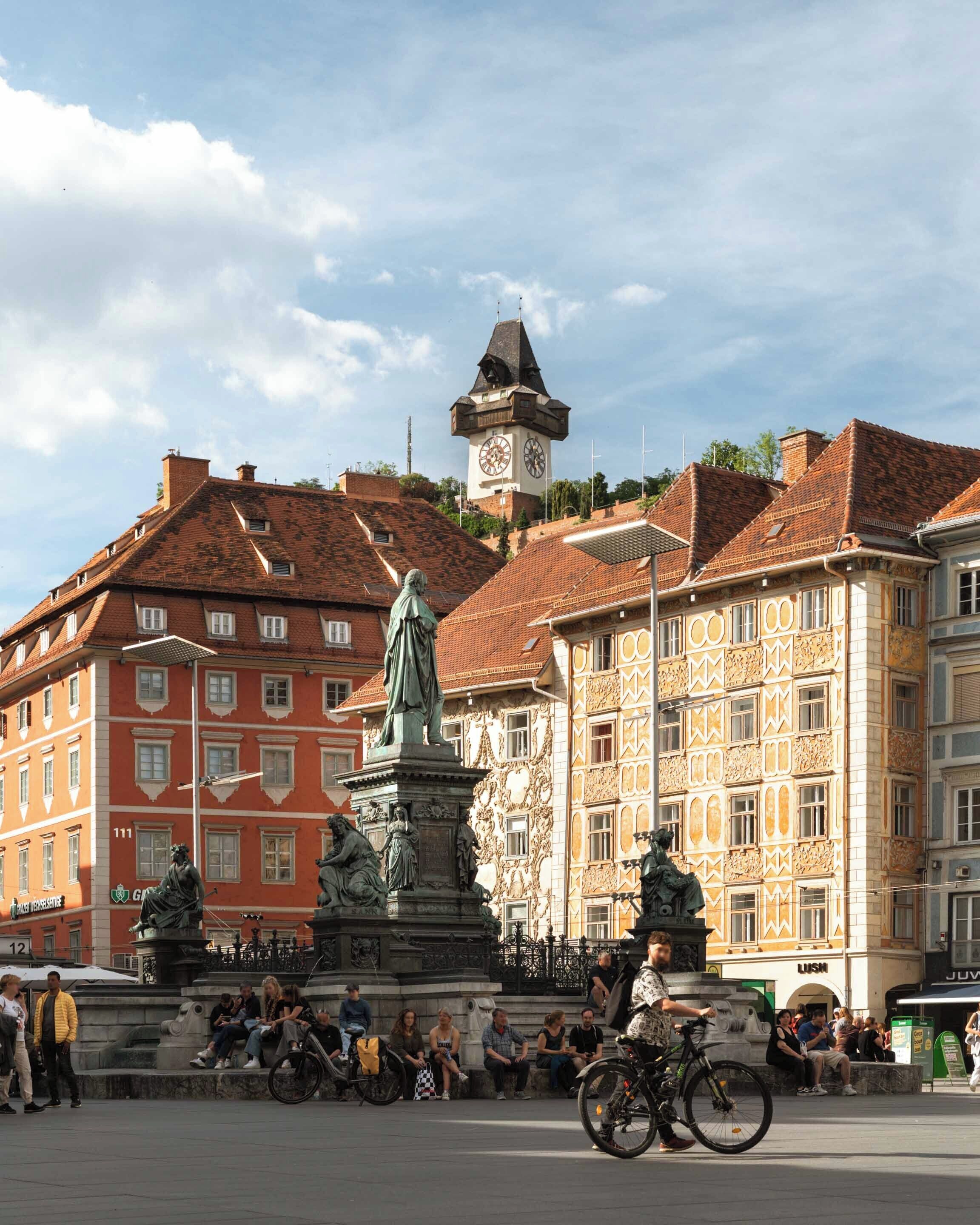 A public square with a statue, historic buildings, and a clock tower.
