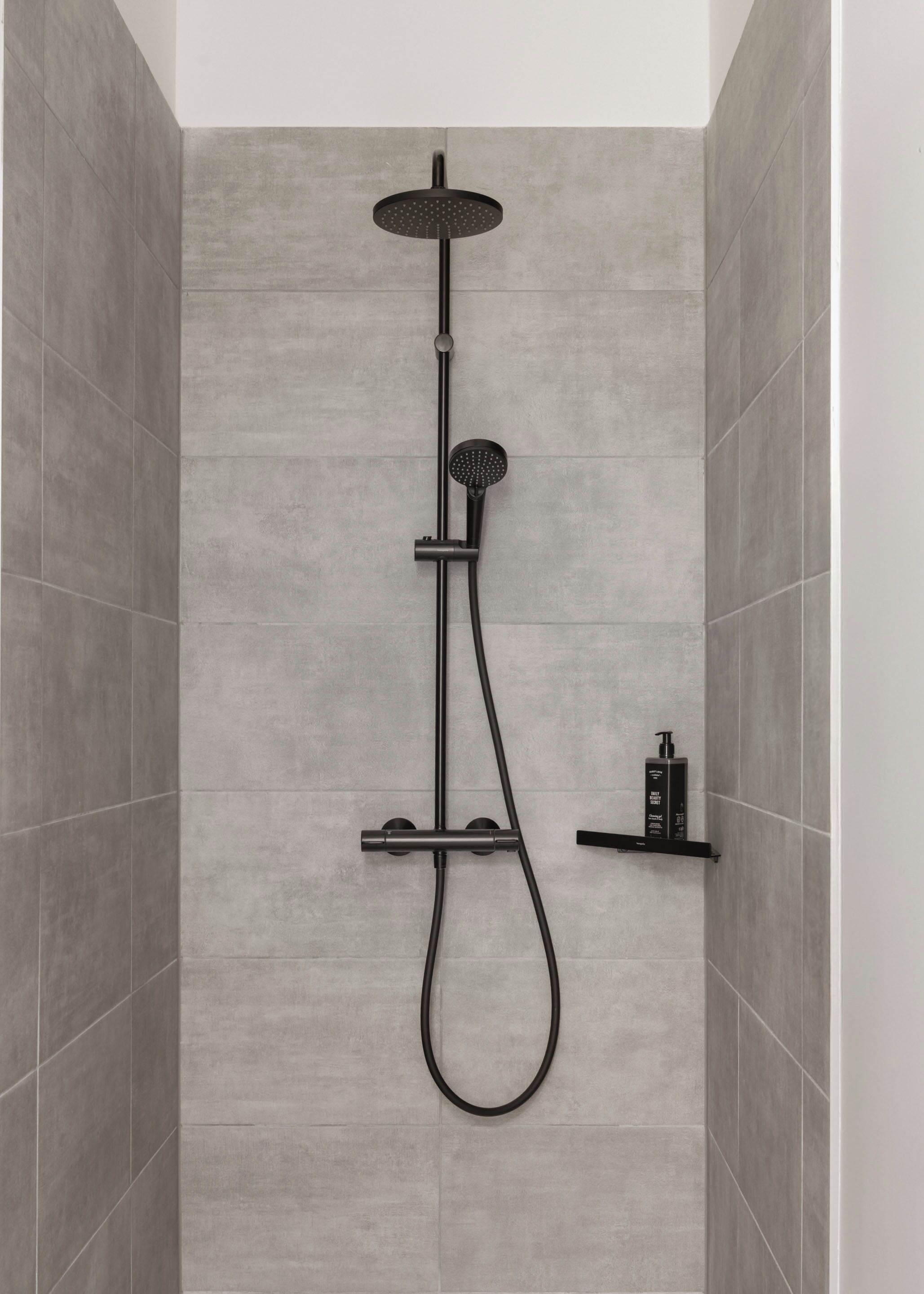 A modern shower with a handheld showerhead, a rain showerhead, and a handheld shower attachment.