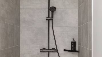 A modern shower with a handheld showerhead, a rain showerhead, and a handheld shower attachment.